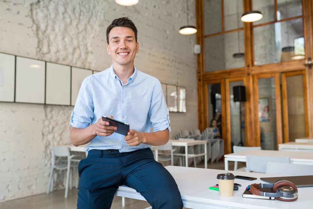 junger-man-laechelnd-in-buero-mit-tablet